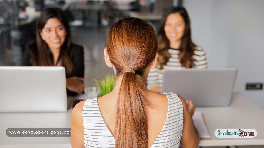 A job candidate sitting across from two interviewers at a modern office, engaged in a professional interview discussion.